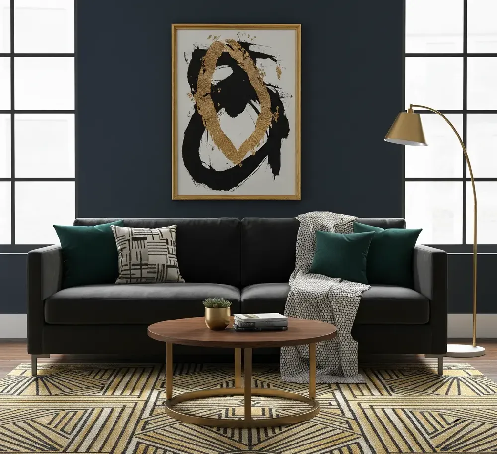 A sophisticated living room featuring a sleek black sofa adorned with dark green and patterned black-and-white throw pillows, and a light-colored woven throw blanket. A round wooden coffee table with a gold metal base sits on a striking geometric area rug in mustard yellow, black, and off-white patterns. The walls are a deep navy blue, with a prominent abstract painting in black and gold above the sofa. Large black-framed windows flank the sofa, and a gold arc floor lamp stands to the right.