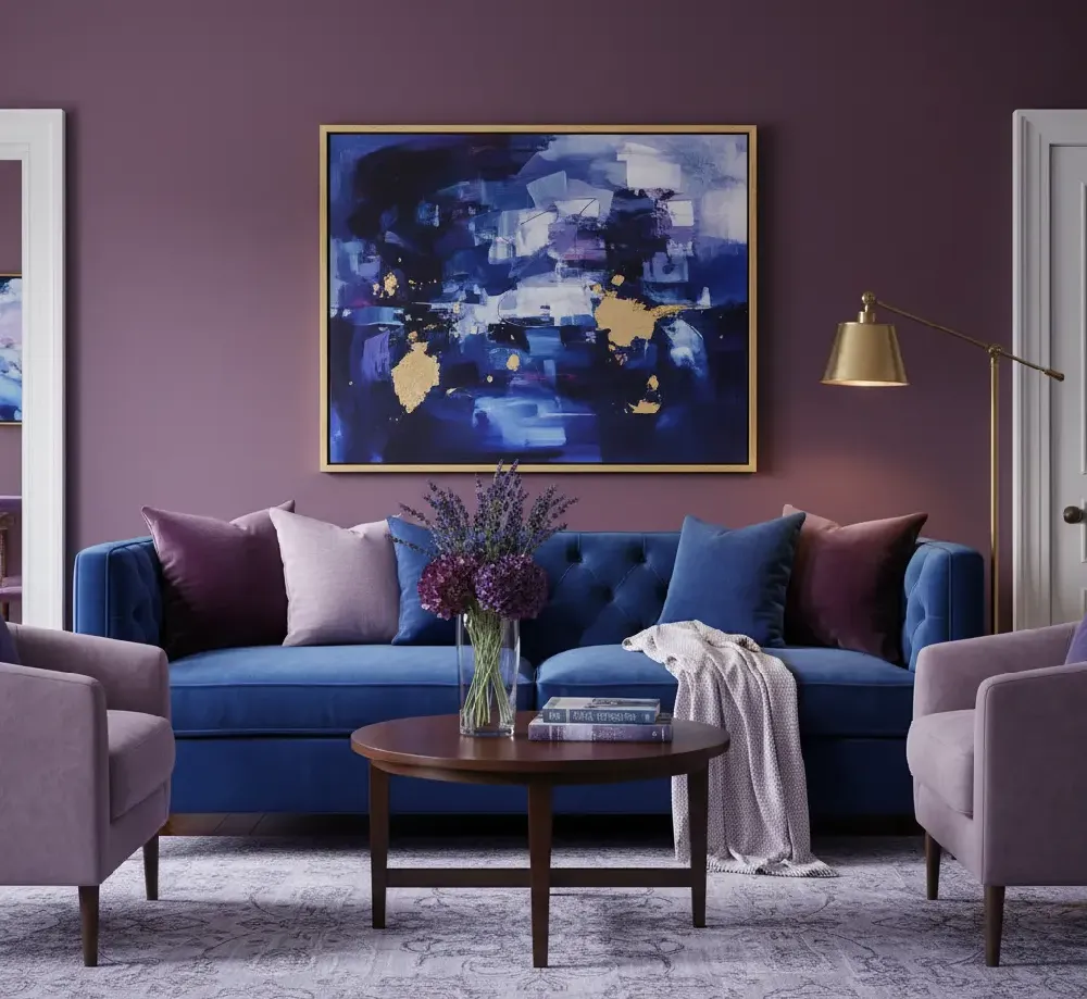 A sophisticated, jewel-toned space featuring a royal blue sofa. Deep aubergine or plum velvet throw pillows and a patterned rug incorporating rich purple, gold, and lavender accents elevate the room, giving it a regal, opulent, and luxurious feel.